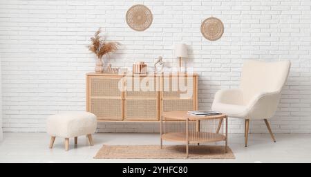 Commode en bois avec décor, fauteuil, table et pouf dans la chambre Banque D'Images