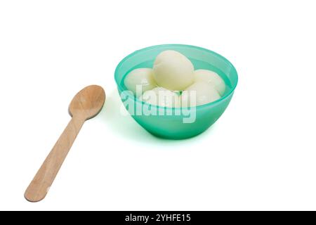 Une vue de dessus du traditionnel Rasgulla indien servi dans un bol en plastique vert, accompagné d'une cuillère en bois. Idéal pour les occasions festives indiennes. Banque D'Images