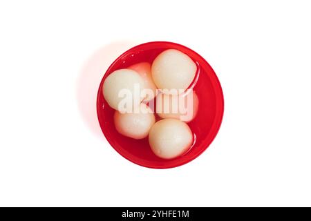 Vue de dessus de rasgullas doux traditionnels indiens trempés dans du sirop de sucre, présentés dans un bol rouge sur un fond blanc. Banque D'Images