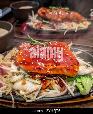 Gros plan de filet de saumon teriyaki japonais chaud à la vapeur avec des légumes sur une plaque chauffante dans le restaurant Banque D'Images