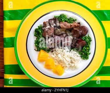 La meilleure et la plus traditionnelle feijoada brésilienne dans le monde servie sur une assiette verte et jaune Banque D'Images