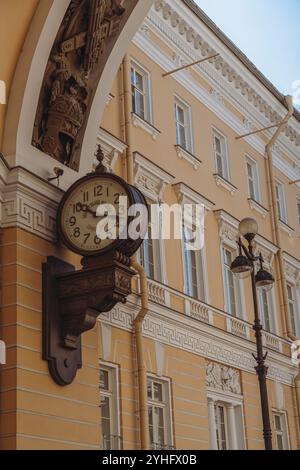 Gros plan d'une horloge vintage montée sur la façade d'un bâtiment historique avec des détails architecturaux classiques, sous la lumière du jour douce. Élégant scen urbain Banque D'Images