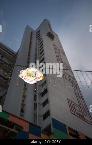Un panneau lumineux suspendu de Chinatown Singapore au premier plan regardant jusqu'à la tour d'habitation Block 335B au crépuscule Banque D'Images