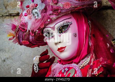 Gros plan d'un artiste au Carnaval de Venise, vêtu d'un costume rose et violet extravagant. Banque D'Images