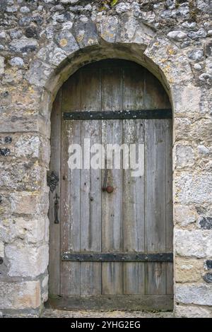Vieille porte en bois voûtée avec des luminaires en métal dans un mur de pierre, se déguiser Banque D'Images