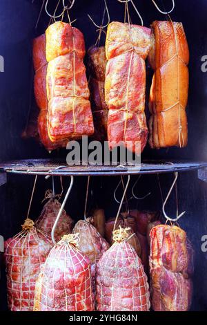 C'est la tradition culinaire composée de diverses coupes de viande fumée un bacon de fumeur accroché sur des crochets qui crée une délicieuse friandise dans Smokehouse Banque D'Images