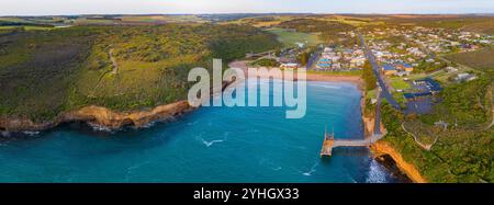 Panorama aérien d'une ville côtière nichée derrière une petite baie le long d'une côte accidentée à Port Campbell sur la Great Ocen Road à Victoria, en Australie Banque D'Images