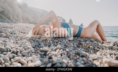 Femme blonde se relaxant sur une plage de galets Banque D'Images