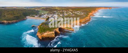 Panorama aérien d'une ville côtière nichée derrière une petite baie le long d'une côte accidentée à Port Campbell sur la Great Ocen Road à Victoria, en Australie Banque D'Images