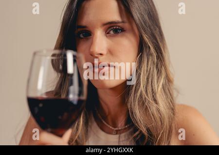 Belle jeune femme dégustation de vin avec une expression ciblée, portrait de style de vie moderne avec une esthétique élégante Banque D'Images