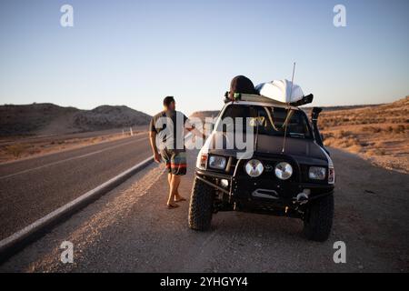 Au coucher du soleil, un homme bronzé grimpe dans son ute 4x4 garé le long de la Northwest Coastal Highway en Australie occidentale. Banque D'Images