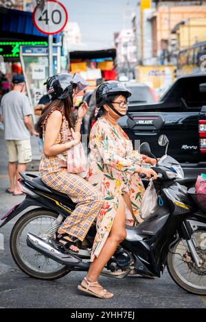 Deux filles thaïlandaises assises sur une moto ou un scooter font leur chemin le long de soi Buakhao, Pattaya City, Thaïlande. Banque D'Images