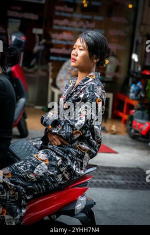 Deux filles thaïlandaises assises sur une moto ou un scooter font leur chemin le long de soi Buakhao, Pattaya City, Thaïlande. Banque D'Images