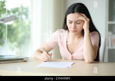 Femme asiatique inquiète lisant le contrat avant de signer dans un bureau à la maison Banque D'Images