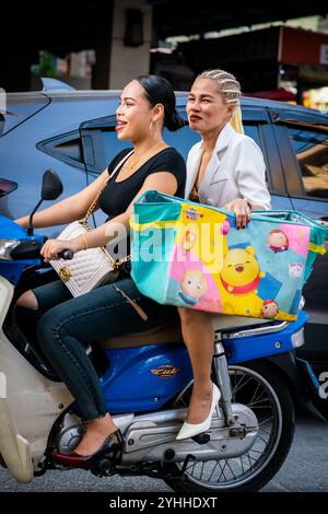 Deux filles thaïlandaises assises sur une moto ou un scooter font leur chemin le long de soi Buakhao, Pattaya City, Thaïlande. Banque D'Images