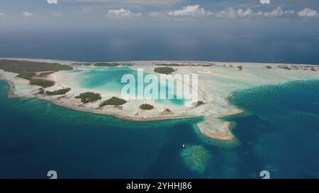 Vue aérienne de Rangiroa, le plus grand atoll de l'archipel des Tuamotus, en Polynésie française, présentant un lagon turquoise vibrant, des récifs coralliens et une végétation luxuriante sous un ciel nuageux. Paradis naturel sauvage isolé Banque D'Images