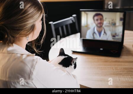 Femme avec chat assistant à la consultation médicale en ligne. Santé virtuelle, télémédecine et concept de confort à domicile. Banque D'Images