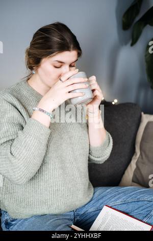 Femme enceinte avec une boisson chaude, embrassant la vie lente. Maternité intentionnelle, soins personnels et calme pendant la grossesse. Banque D'Images