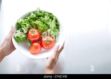 Main de femme tenant des légumes dans un bol dans la cuisine Banque D'Images