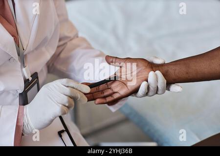 Vue de dessus gros plan du dermatologue inspectant soigneusement les mains d'un patient méconnaissable dans l'espace de copie clinique Banque D'Images