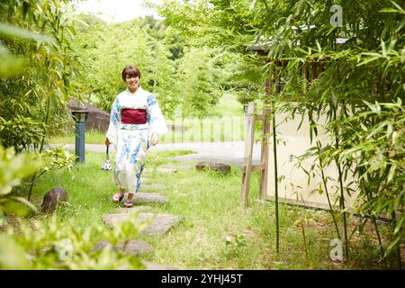 Femme en yukata marchant dans le jardin japonais Banque D'Images