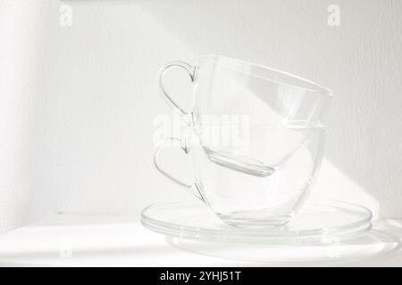 Tasse en verre et soucoupe placées sur une plaque blanche à pâtisserie Banque D'Images