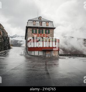 Hôtel Belvédère sur le col de Furka. Vieil hôtel abandonné dans l'épingle à cheveux du célèbre col de montagne Furka. Nuages de vapeur planant en arrière-plan. Banque D'Images