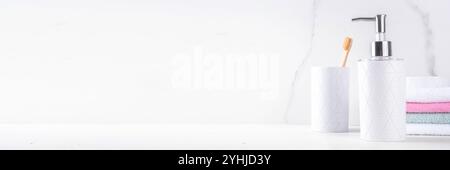 Étagère de salle de bain simple fond blanc. Distributeur de savon, gel douche, porte-savon, verre avec brosses à dents, pile de serviettes sur le comptoir. Maquette pour Banque D'Images