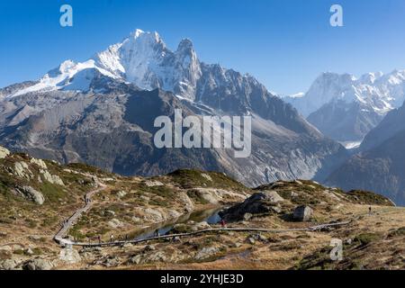 Randonneurs marchant le long d'une passerelle en bois dans une réserve naturelle avec une grande montagne en arrière-plan Banque D'Images