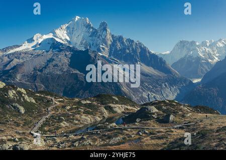 Randonneurs marchant le long d'une passerelle en bois dans la réserve naturelle des aiguilles rouges avec une grande montagne en arrière-plan Banque D'Images