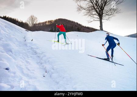 Deux skieuses nordiques féminines sur une piste d'hiver enneigée avec un magnifique Sunset Sky en arrière-plan Banque D'Images