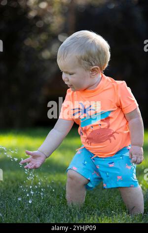 Petit enfant mettant sa main dans des gouttes d'eau. Banque D'Images