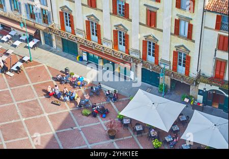 Vue de dessus sur les petites tables et parasols des restaurants en plein air sur la Piazza Vecchia depuis la tour de l'horloge de Palazza della Podesta, Bergame, Italie Banque D'Images