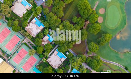 Vue panoramique de haut en bas d'un complexe hôtelier comprenant villas, piscines et courts de tennis au milieu d'un cadre naturel tranquille. Banque D'Images