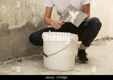 Femme plâtrage mur avec mastic-couteau. Fixation de la surface murale et préparation pour la peinture. Projet d'amélioration du logement DIY. Banque D'Images