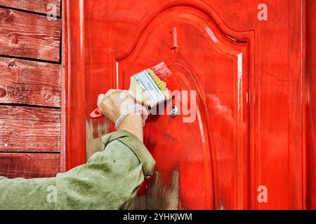 La porte d'entrée en acier est peinte en rouge avant que la maison de campagne en bois soit louée. Banque D'Images