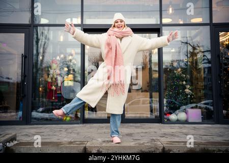 Une femme d'âge moyen aux cheveux blonds aime se divertir en ligne tout en repassant dans son confortable salon, mettant en valeur le multitâche. Banque D'Images