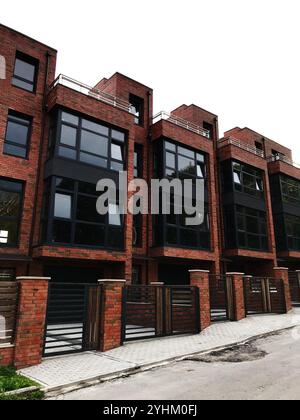 Cette image met en valeur une rangée de maisons de ville modernes en brique avec de grandes fenêtres et une architecture contemporaine. Parfait pour illustrer la vie urbaine, re Banque D'Images