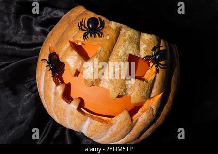 Décor d'Halloween - beaucoup d'araignées noires sur une veilleuse orange. Sur un fond noir, placez-le pour le texte. Banque D'Images