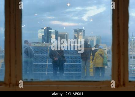 Vue à travers la fenêtre mouillée du pont extérieur du ferry avec les passagers regardant Gênes skyline, Italie Banque D'Images