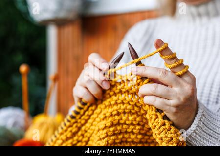 Tricoter avec de la laine. Femme en pull en laine tricote des vêtements chauds de fil jaune Banque D'Images