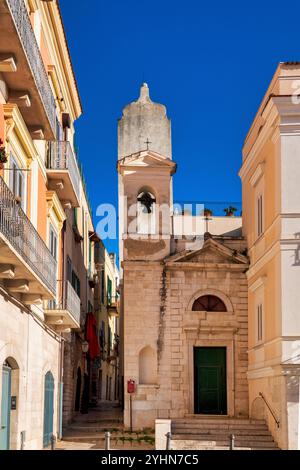 La modeste façade de Chiesa di San Donato à Trani, en Italie, avec une entrée simple et une tour de l'horloge médiévale adjacente. Banque D'Images