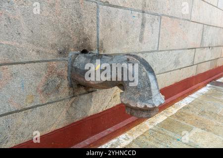 Ancien bec d'eau en pierre sur un mur de granit, mettant en valeur l'artisanat traditionnel et les détails architecturaux. Banque D'Images