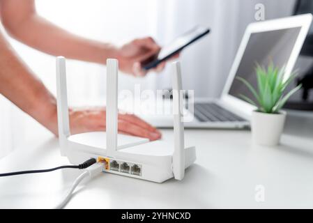 Personne connectant un routeur wi-fi moderne sur une table lumineuse dans le salon Banque D'Images