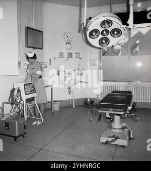 1979, historique, une infirmière, une sœur de théâtre au travail dans une salle d'opération d'hôpital ou un théâtre, Angleterre, Royaume-Uni. L'image montre le lit d'opération et la lampe chirurgicale ci-dessus. Banque D'Images