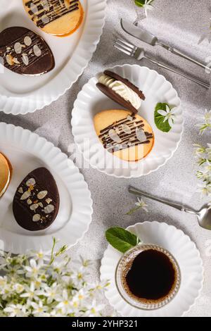 Délicieux biscuits en forme d'oeuf de pâques garnis de crème, décorés de chocolat et d'amandes, servis avec du café pour un petit déjeuner festif Banque D'Images