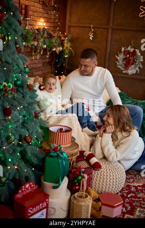 Famille heureuse serrée chaleureusement à côté du sapin de Noël Banque D'Images