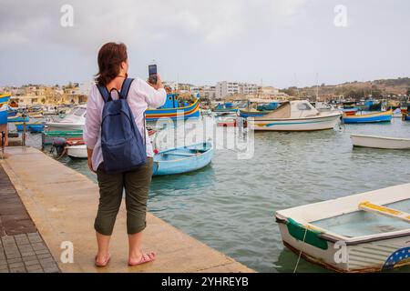 Femme voyageuse filmant vidéo dans le village de pêcheurs touristique Marsaxlokk à Malte Banque D'Images