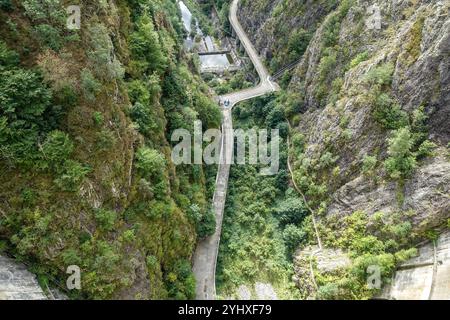 Route de montagne sinueuse d'accès au barrage coupant à travers une gorge boisée verte profonde avec des falaises rocheuses abruptes des deux côtés, au barrage de Vidraru, Transfăgărășan Banque D'Images