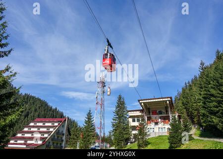 Téléphérique rouge Transfagarasan montant au-dessus d'un paysage de montagne boisé avec Lodge et ciel bleu, vers le lac Balea, Roumanie Banque D'Images